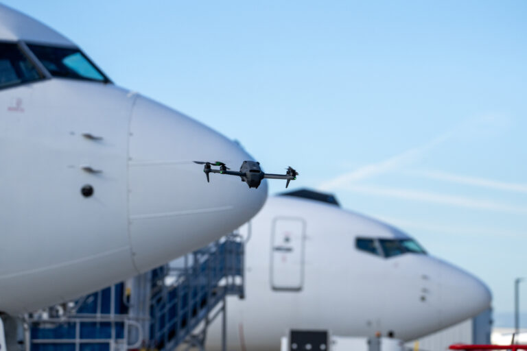 Drone flying between parked commercial aircraft during an aviation production.