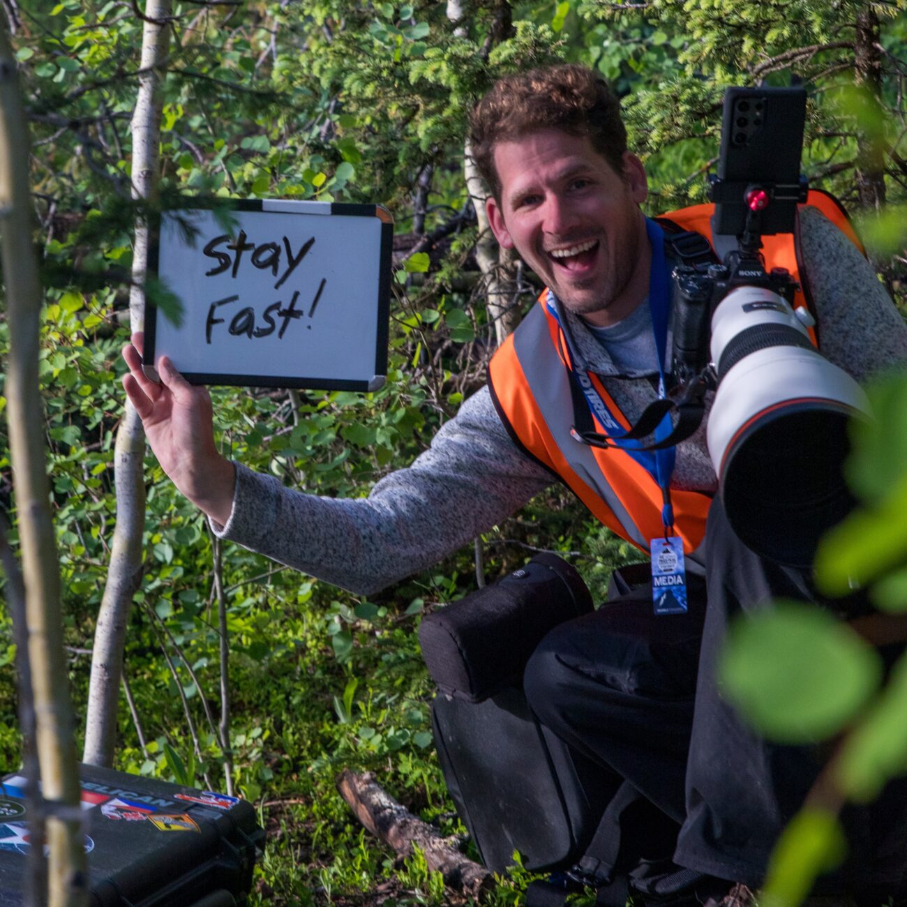 Camera operator Philip A. Young holding a Stay Fast sign beside the Pikes Peak race course.