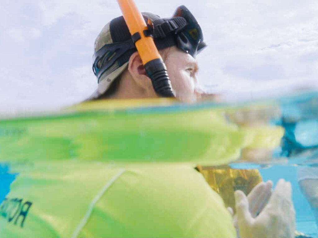 Diver testing an underwater camera at the surface of a swimming pool.