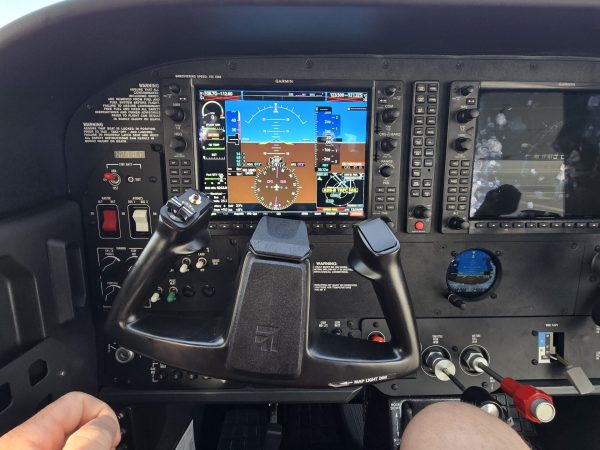 Dual-screen glass cockpit with digital flight instruments inside a small aircraft.