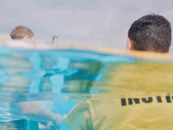 Crew preparing an underwater camera system at the surface of a swimming pool.
